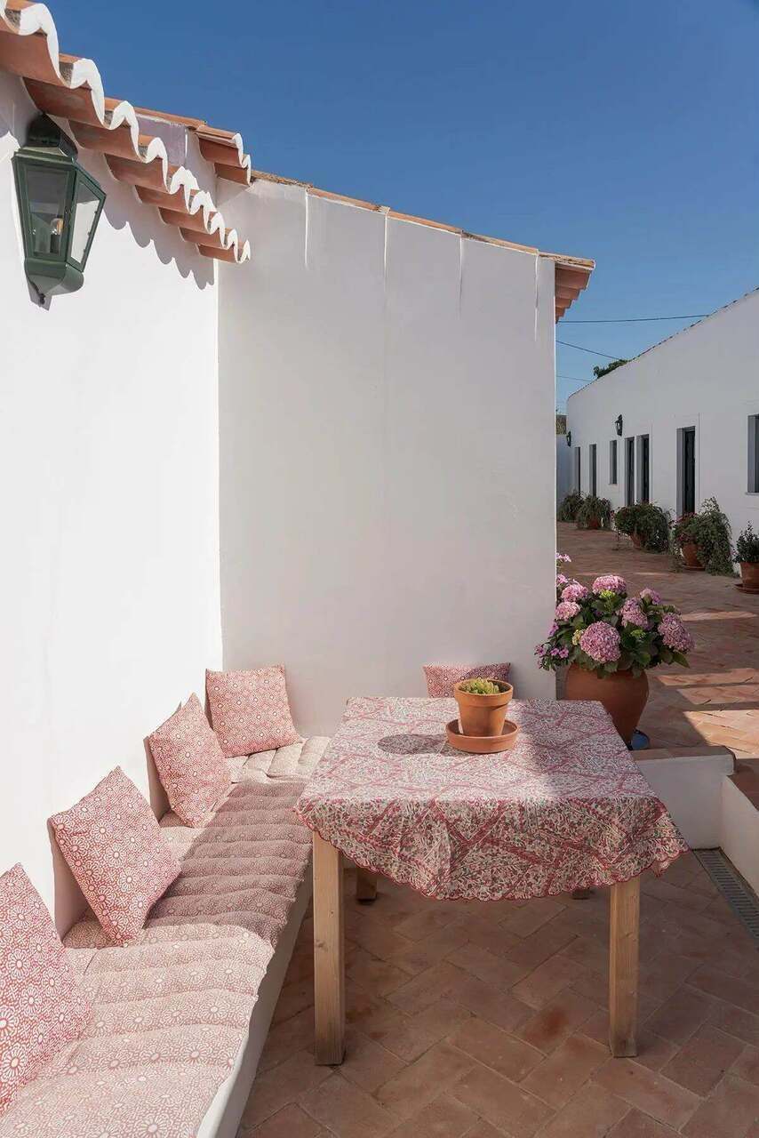 A corner of the outdoor table, cushions on the bench